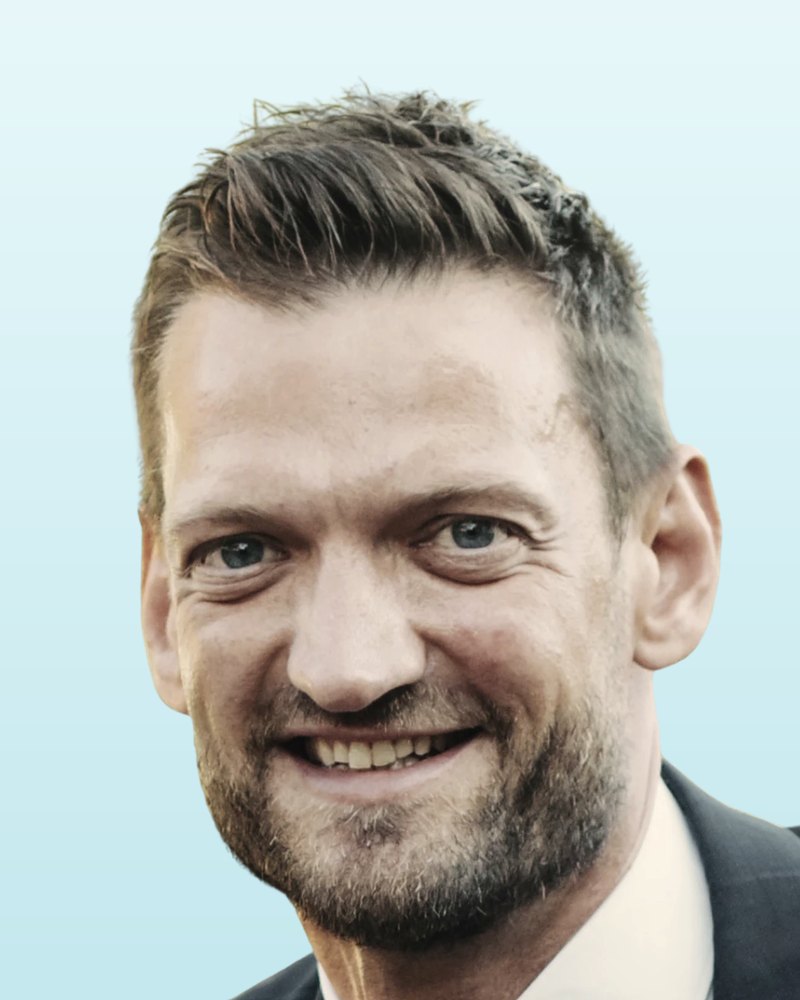 Nico Rößler, Inhaber von Cleverfritz, lächelnd im dunklen Anzug